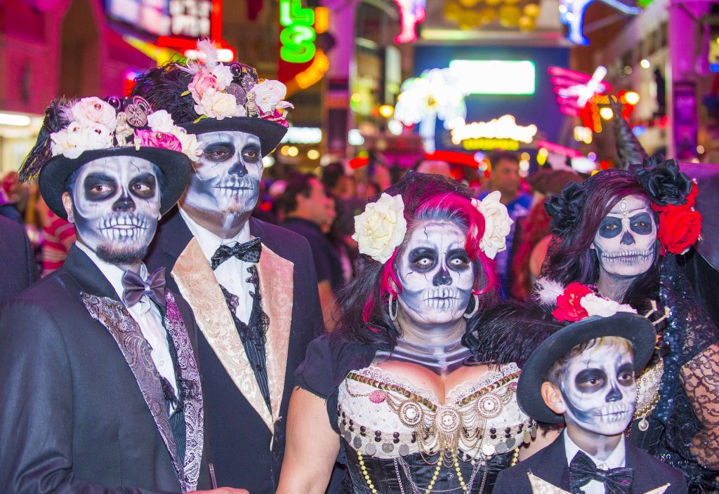 Group of people celebrating Day of the Dead with skull face paintings and black tie attire
