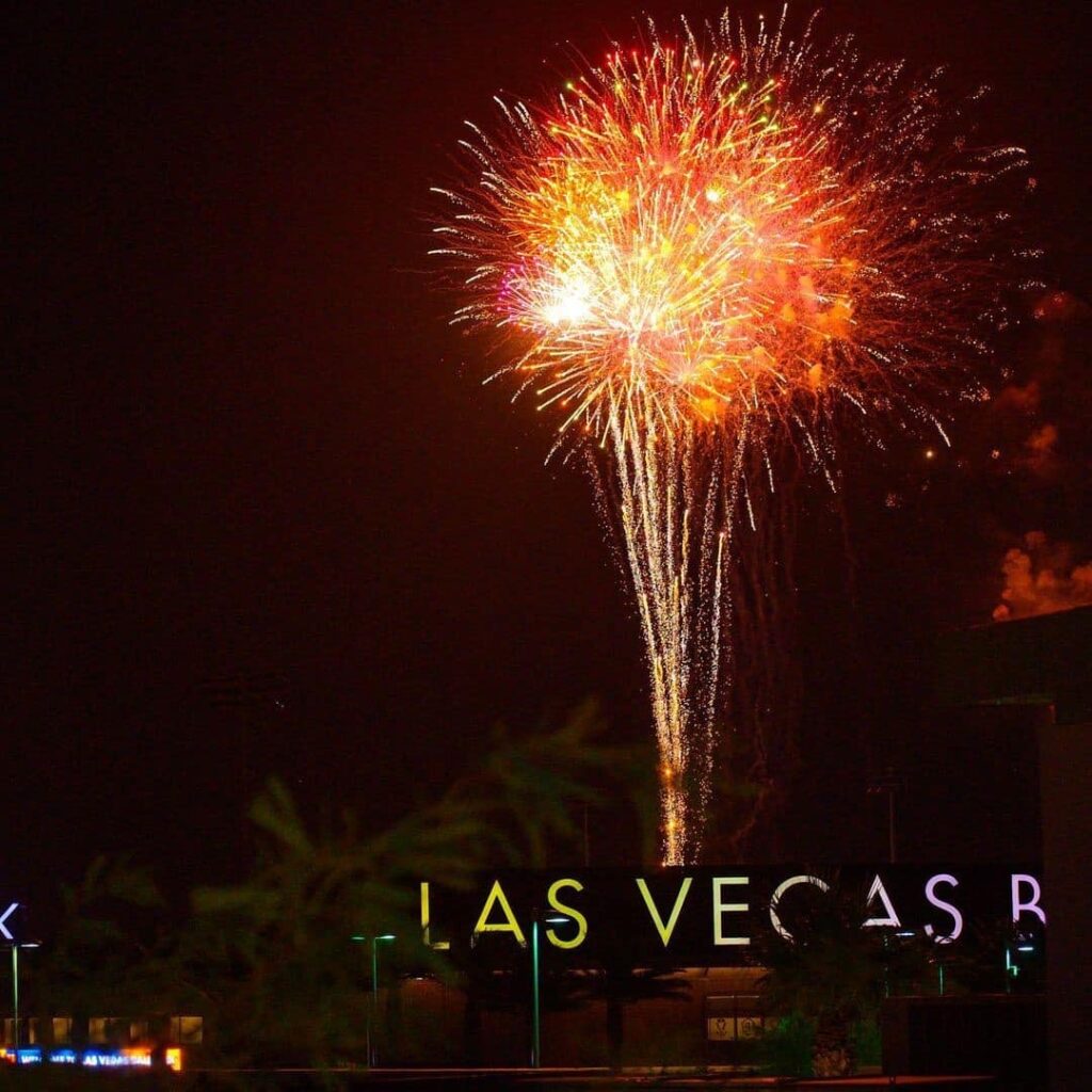 fireworks shoot into the sky with vegas street sign in foreground